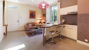 A modern kitchen with a bar area, a dining area with a sofa, and a large window.