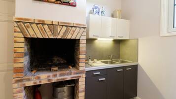 Una cocina con horno de ladrillo, un lavabo, armarios y un elemento decorativo en la pared.