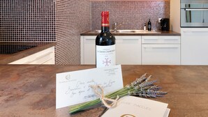 A bottle of Chateau La Croix Chaignée wine, a handwritten welcome note, and a guide on a kitchen counter.