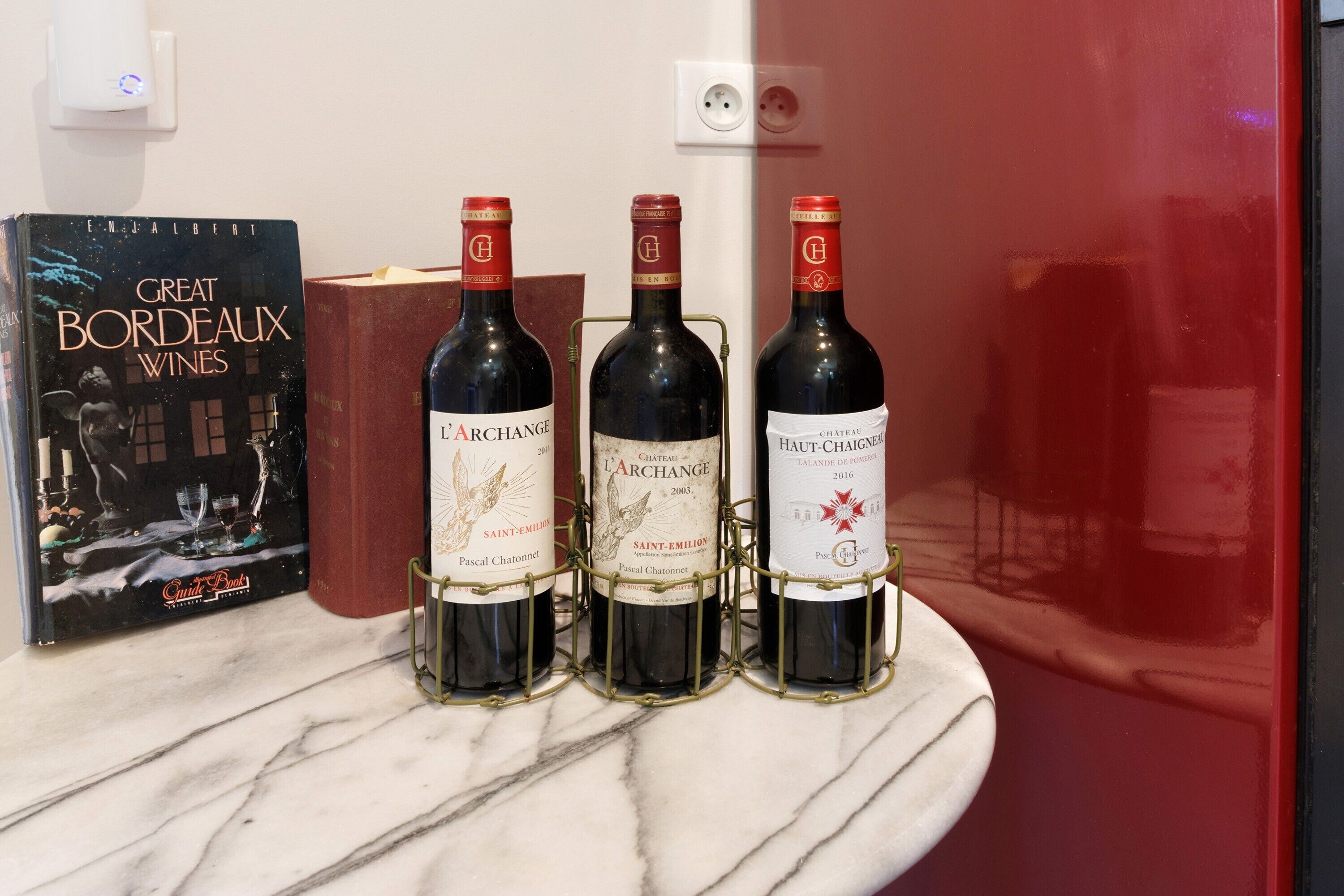 Eine Marmarbeplatte mit drei Weinflaschen und einem Buch mit dem Titel 'Great Bordeaux Wines'.