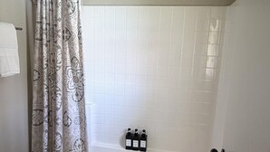 Un bagno con un water, una tenda da doccia, una vasca e un piccolo tappeto.