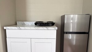 Una cucina con un piano di lavoro bianco, un fornello nero e un frigorifero in acciaio inossidabile.