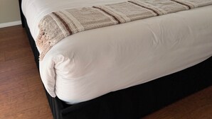 Un letto con un cuscino con la scritta 'welcome home', una testata scura e una finestra con persiane.