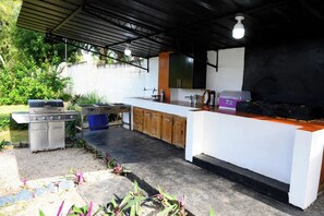 Une cuisine extérieure équipée d’un barbecue, de meubles en bois et d’un plan de travail.