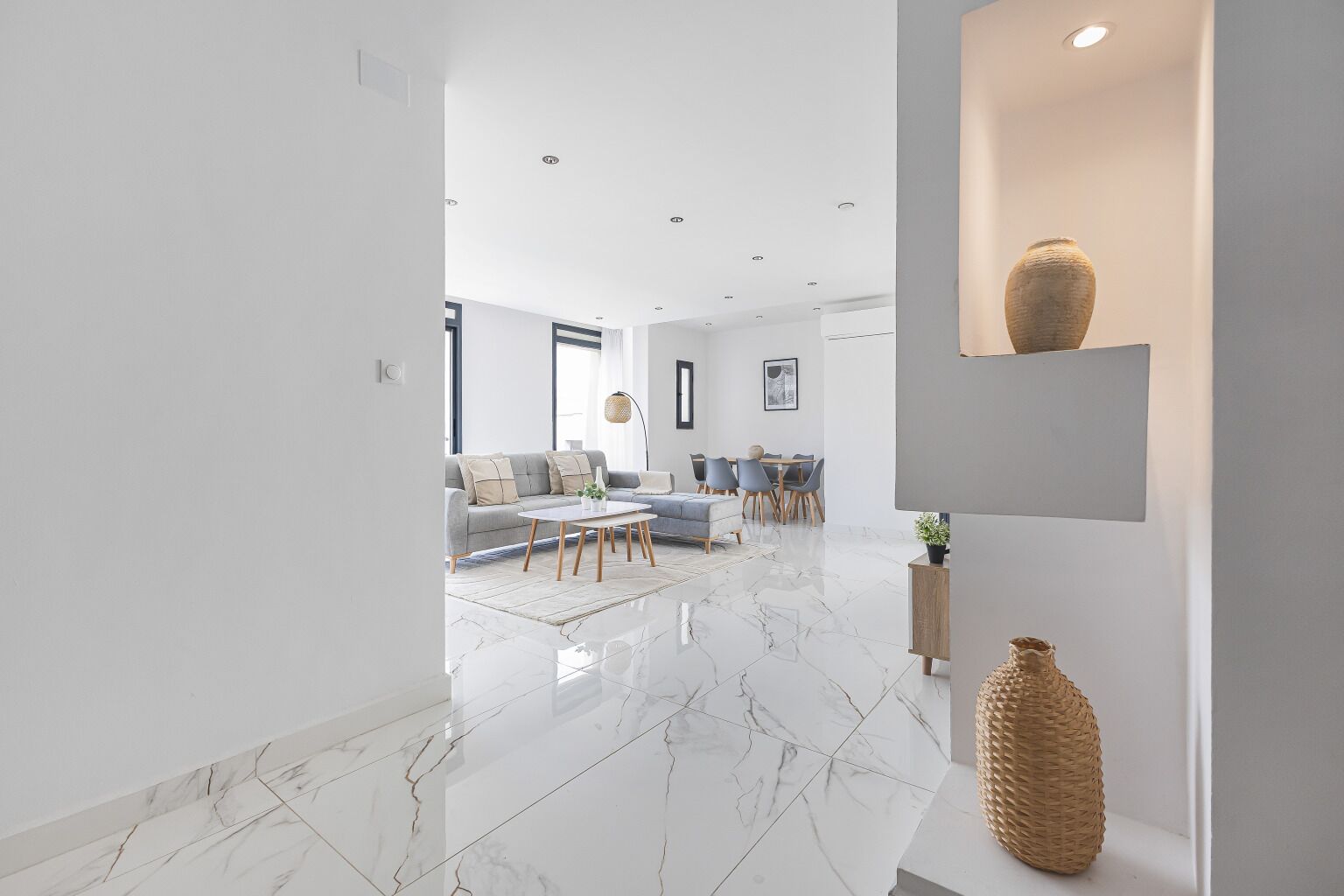 A modern living room with a marble floor, a sofa, a coffee table, and a dining area with chairs and a table.