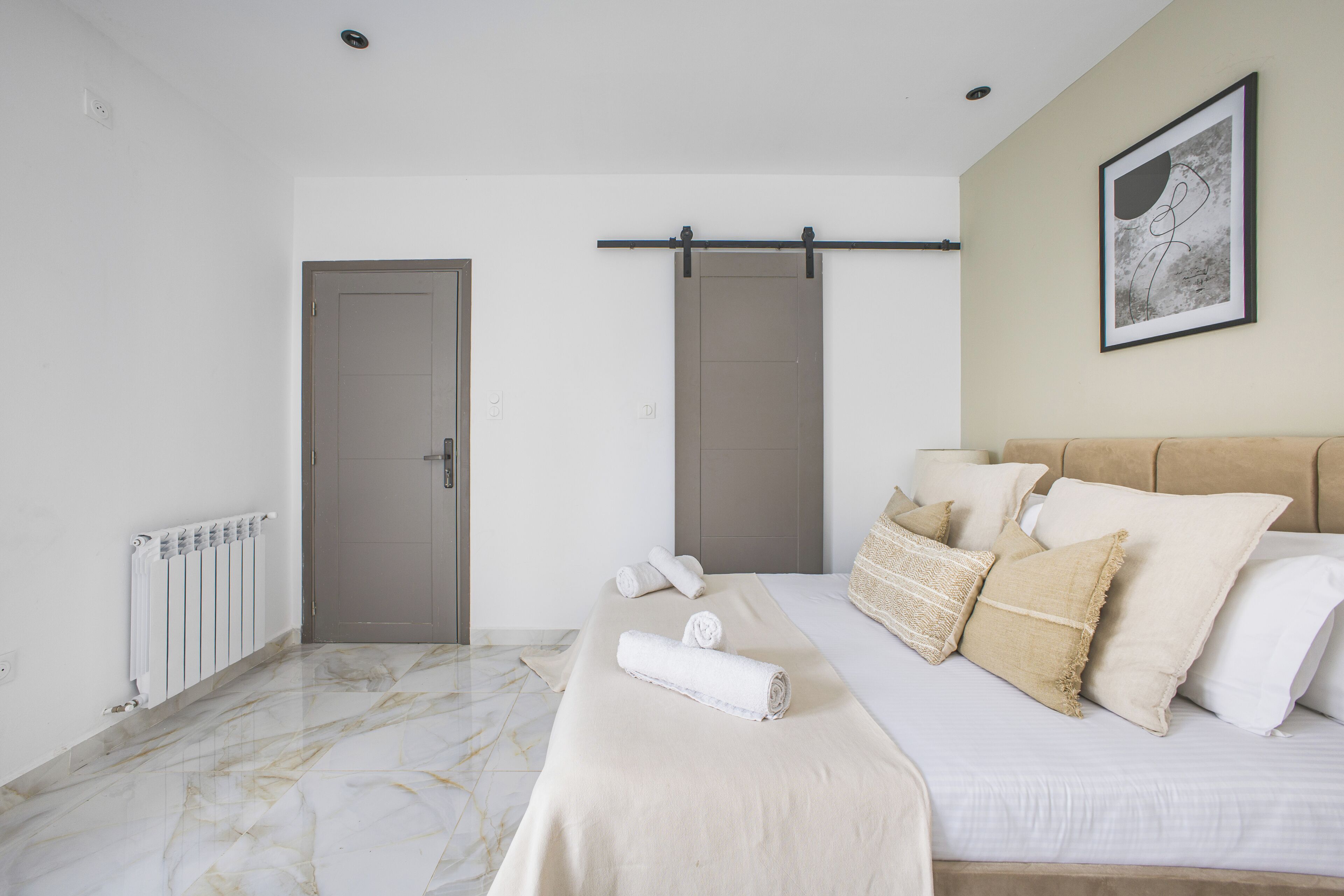 Un dormitorio con cama, un radiador, una puerta y una obra de arte colgada en la pared.