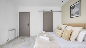 Un dormitorio con cama, un radiador, una puerta y una obra de arte colgada en la pared.