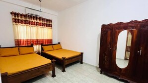 A bedroom with two single beds, a wardrobe, and a window with curtains. - Kamaleswari Villa Trincomalee | 3BR House | 2km to Beach | Family Stay (Trincomalee)