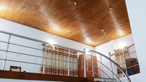 A staircase with metal railings, wooden ceiling, and a view of a room with a bed and a wardrobe. - Kamaleswari Villa Trincomalee | 3BR House | 2km to Beach | Family Stay (Trincomalee)