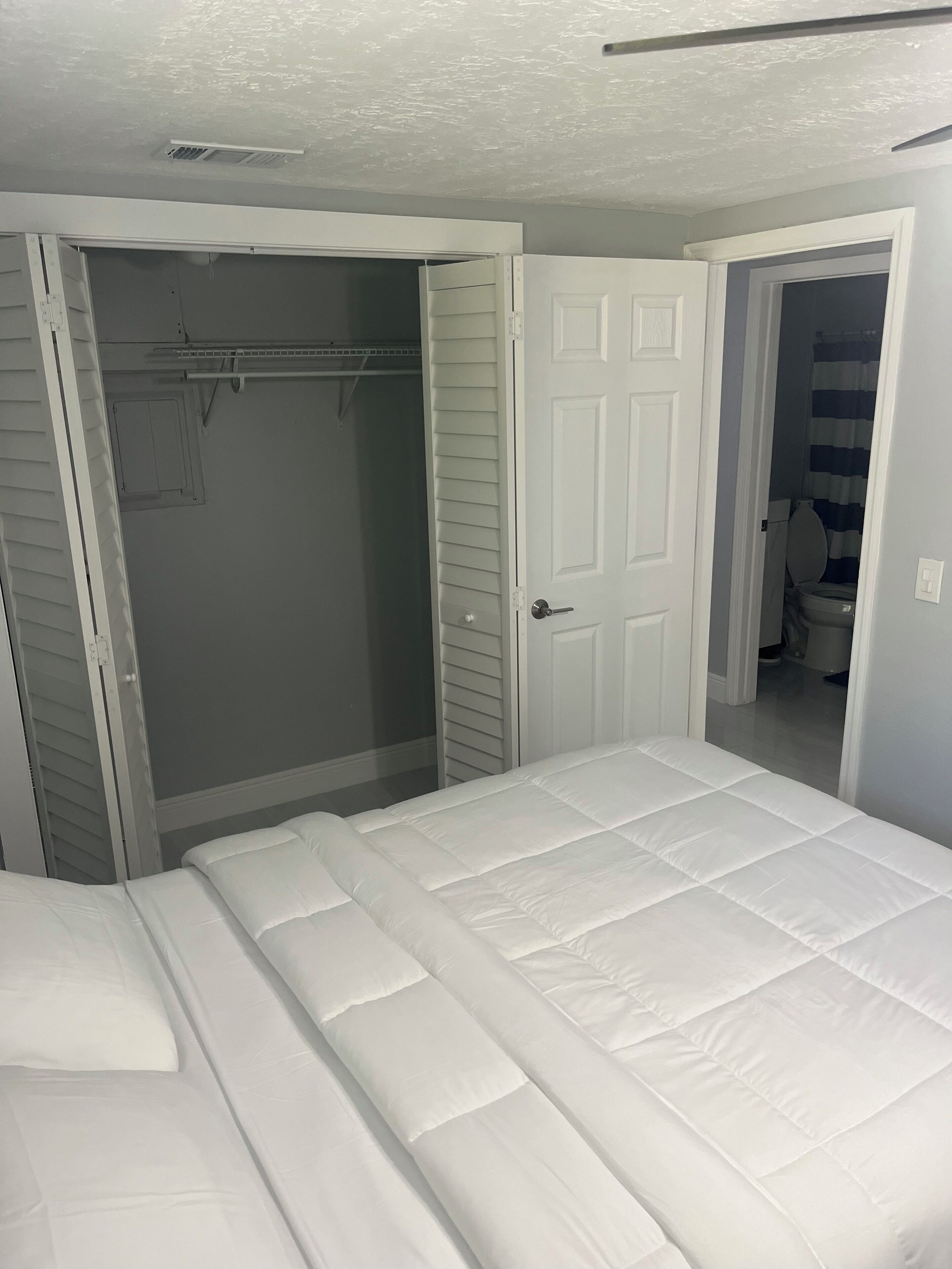 Un dormitorio con cama, armario y baño.