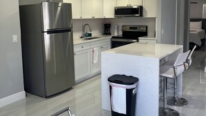 Una cocina moderna con electrodomésticos de acero inoxidable, una isla central y taburetes de bar.