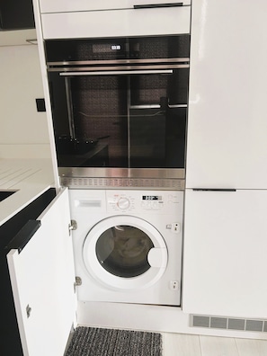 A compact washer and dryer unit with a digital display, control panel, and a small vent at the bottom. - Stylish 2Bed Flat-Fast WiFi-Close to Shops, Restaurants & Train Station-Sleeps 5 (Croydon)