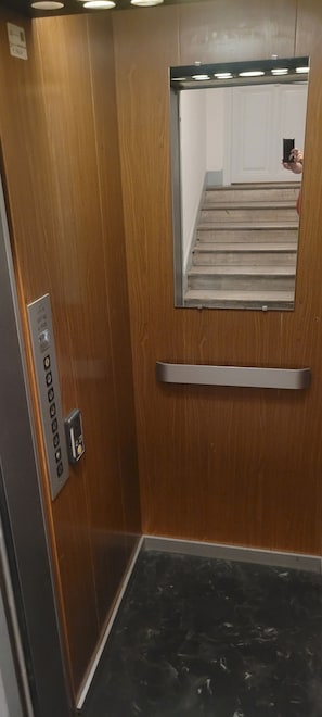 An elevator interior with a wooden door, a metal handle, and a small mirror on the wall. - Air-conditioned apartment in the heart of town, just 7' from the beach! (Nice)