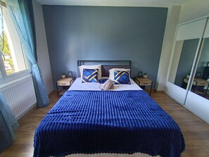Un dormitorio con cama, dos mesitas de noche, un espejo y una ventana con cortinas.