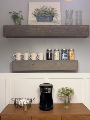 A kitchen counter with a coffee maker, a basket, and a vase. - Cozy High Point Stay (High Point)