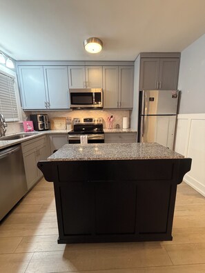 A modern kitchen with grey cabinets, stainless steel appliances, and a granite countertop island. - Cozy High Point Stay (High Point)