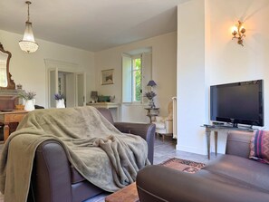 Ein Wohnzimmer mit einer Couch, einem Fernseher und einer Wandlampe.