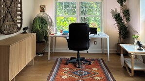 Ein moderner Arbeitsplatz mit Schreibtisch, Stuhl und großem Fenster.