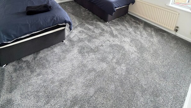 A bedroom with two beds, a window with curtains, a radiator, and a ceiling light fixture. - 3 Bed House Contractor Friendly Long Stays Welcome (Bedford)