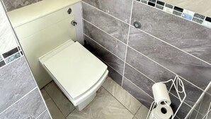 A bathroom with a toilet, a shower area, and a window. - 3 Bed House Contractor Friendly Long Stays Welcome (Bedford)