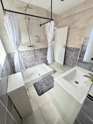 Ein Badezimmer mit Dusche, zwei Waschbecken, einer Badewanne und einem Handtuchhalter.
