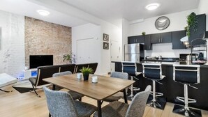 Eine moderne Küche mit schwarzen Schränken, einem Edelstahl-Kühlschrank und einer Bar mit Barhocker.