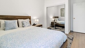 Ein Schlafzimmer mit Bett, Nachttischen, einem Spiegel und einem Kleiderschrank.