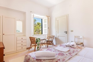 A bedroom with a bed, a desk, two chairs, a dresser, and a window with a view of trees. - Decima Dimora Del Pizzo - Gallipoli (Gallipoli)