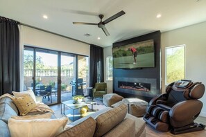 Un salon moderne comprenant un canapé, un fauteuil massant, un téléviseur à écran plat et une cheminée.