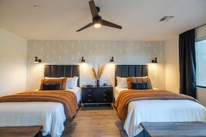 Une chambre d’hôtel avec deux lits, un ventilateur de plafond, des lampes fixées au mur et une fenêtre avec des rideaux.