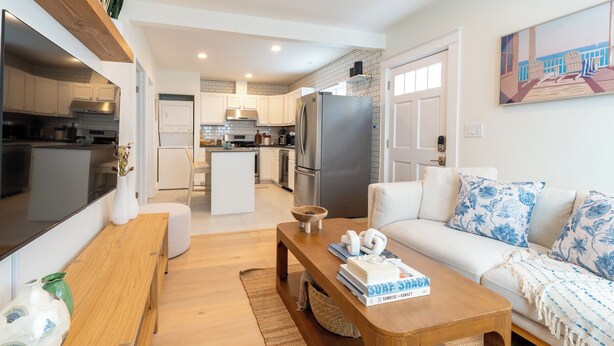 A modern kitchen with white cabinets, a central island, and a large refrigerator. - NEW! Boutique Coastal home Steps from the Beach (Marina del Rey)