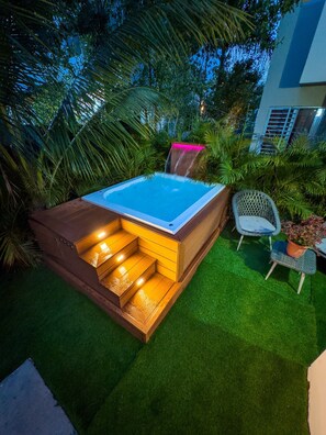 A hot tub with steps, surrounded by lush greenery and a chair. - Milyleo Home, Your Caribbean Hideaway – Private Jacuzzi & Tropical Comfort (Punta Cana)