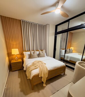 A hotel room with a bed, bedside lamps, a ceiling fan, a large mirror, and a window with curtains. - Milyleo Home, Your Caribbean Hideaway – Private Jacuzzi & Tropical Comfort (Punta Cana)