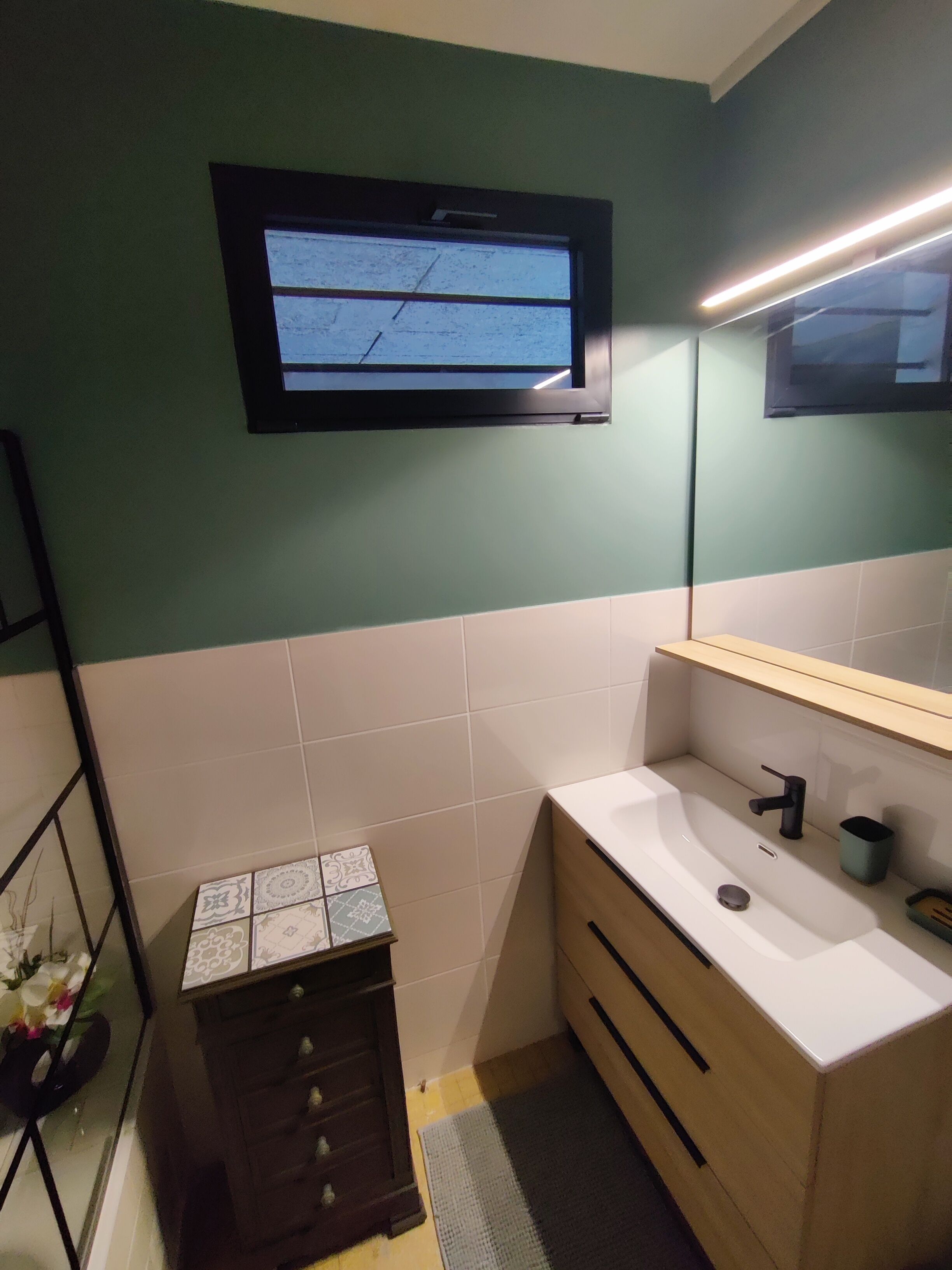 Un baño con lavamanos, espejo y ventana.