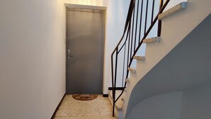 A staircase with a metal railing, a door at the top, and a light fixture on the ceiling. - Le Carpe Diem Apartment, in Langeac, in the heart of the Allier Gorges (Langeac)