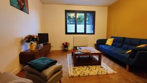 A living room with a sofa, a coffee table, a TV, and a window with a view. - Le Carpe Diem Apartment, in Langeac, in the heart of the Allier Gorges (Langeac)