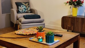 A living room with a sofa, a coffee table with decorative items, and a cabinet with a vase of flowers. - Le Carpe Diem Apartment, in Langeac, in the heart of the Allier Gorges (Langeac)