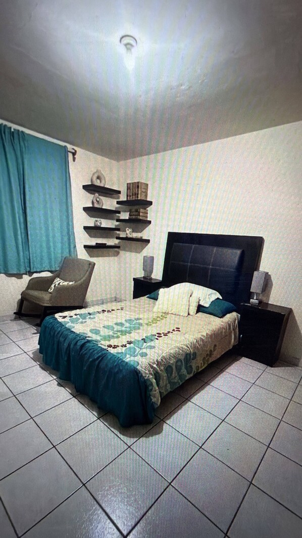 Una camera da letto con un letto, una sedia, un comodino e scaffali a parete.