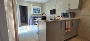A modern kitchen with a flat-screen TV, a kettle, and a microwave. - Cozy 2 Bedroom Cottage (Johannesburg)