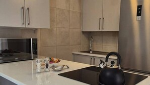 Una cocina moderna con una isla grande, electrodomésticos de acero inoxidable e iluminación colgante.