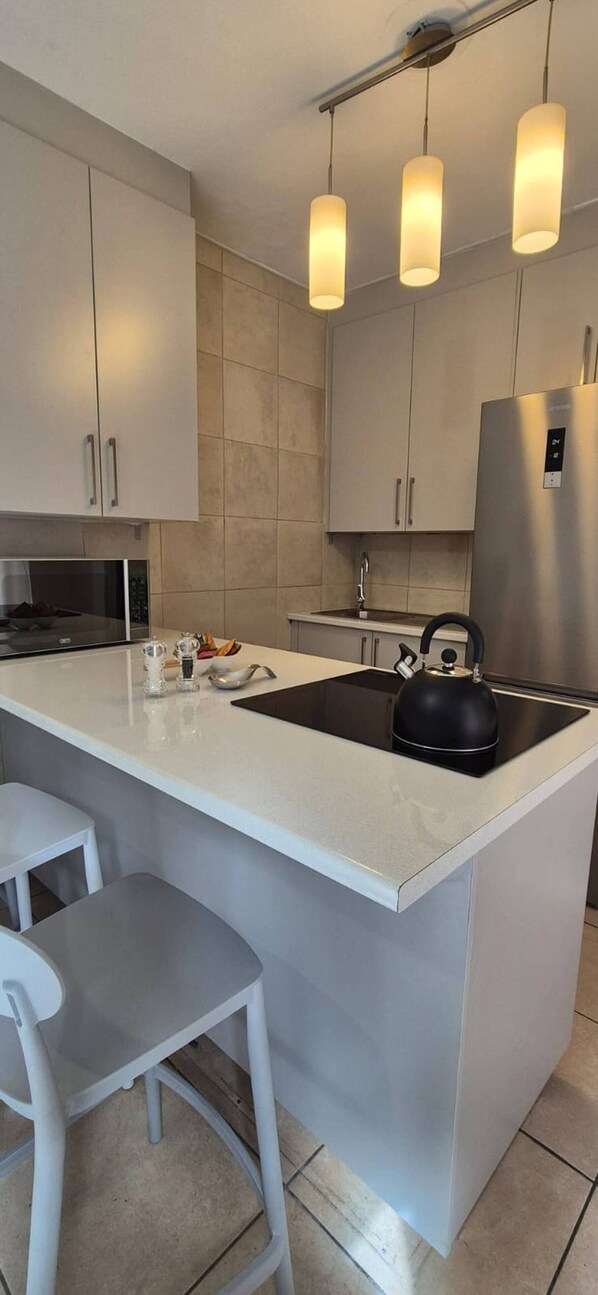 Una cocina moderna con una isla grande, electrodomésticos de acero inoxidable e iluminación colgante.