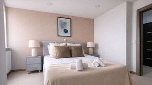 Ein ordentlich eingerichtetes Schlafzimmer mit Bett, Nachttischen und einem gerahmten Bild an der Wand.
