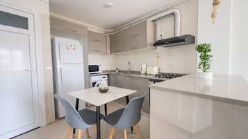 Appartement | Privékeuken | Een koelkast, een oven, een kookplaat, kookgerei, borden en bestek