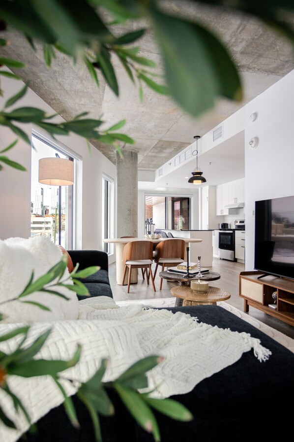 Ein modernes Wohnzimmer mit einer Couch, einem Essbereich und einer Küche im Hintergrund.