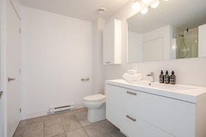 Ein modernes Badezimmer mit Toilette, Waschtisch mit Spiegel und Duschbereich.