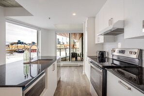 Eine moderne Küche mit einem großen Fenster, Blick auf die Stadt und einem Essbereich mit Tisch und Stühlen.