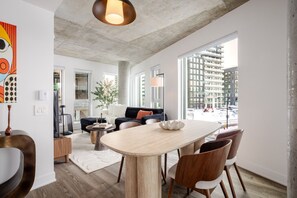Ein modernes Wohnzimmer mit Essbereich, großen Fenstern und Blick auf ein Bauprojekt.