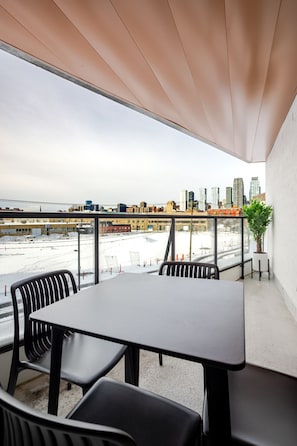 Ein Balkon mit Tisch und Stühlen, einem Blumentopf und Blick auf Stadtpanorama und Strand.