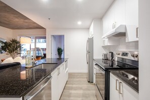 Eine moderne Küche mit einer Granitabdeckung, Edelstahlgeräten und Blick zum Wohnbereich.