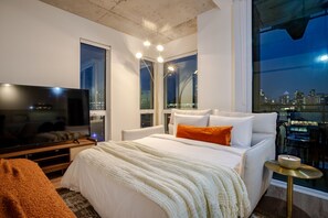 Ein modernes Hotelzimmer mit einem großen Bett, einem Fernseher und Blick auf die Stadt.